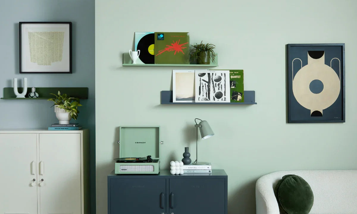 A living room setting showing The Lowdown in Slate and The Midi in Chalk against a sage green wall. Two Ledges hang on the wall, as well as two pieces of artwork.