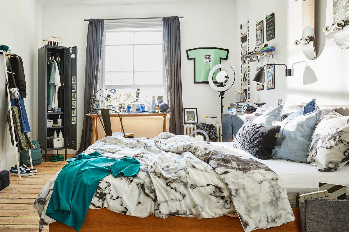 The Skinny locker in Slate, open as a wardrobe in a share house bedroom with a desk by the window and skateboards on the wall