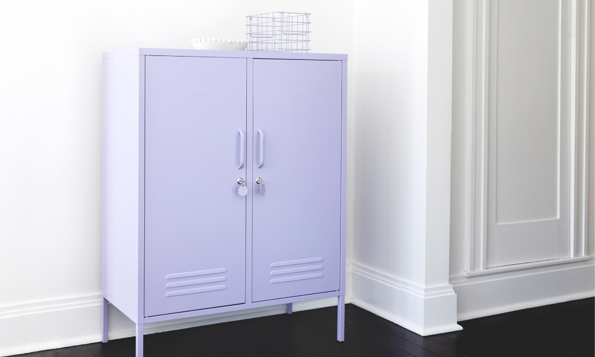 A Lilac Midi locker sits against a white wall with dark wood floors. There is a Lilac Basket and a small white bowl styled on top.