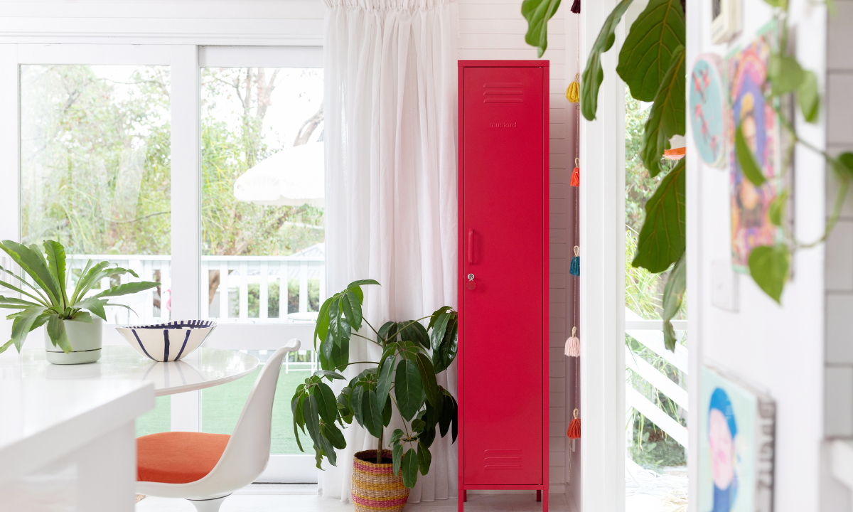 A Skinny locker in Poppy stands out in a white, airy room filled with plants and natural light.