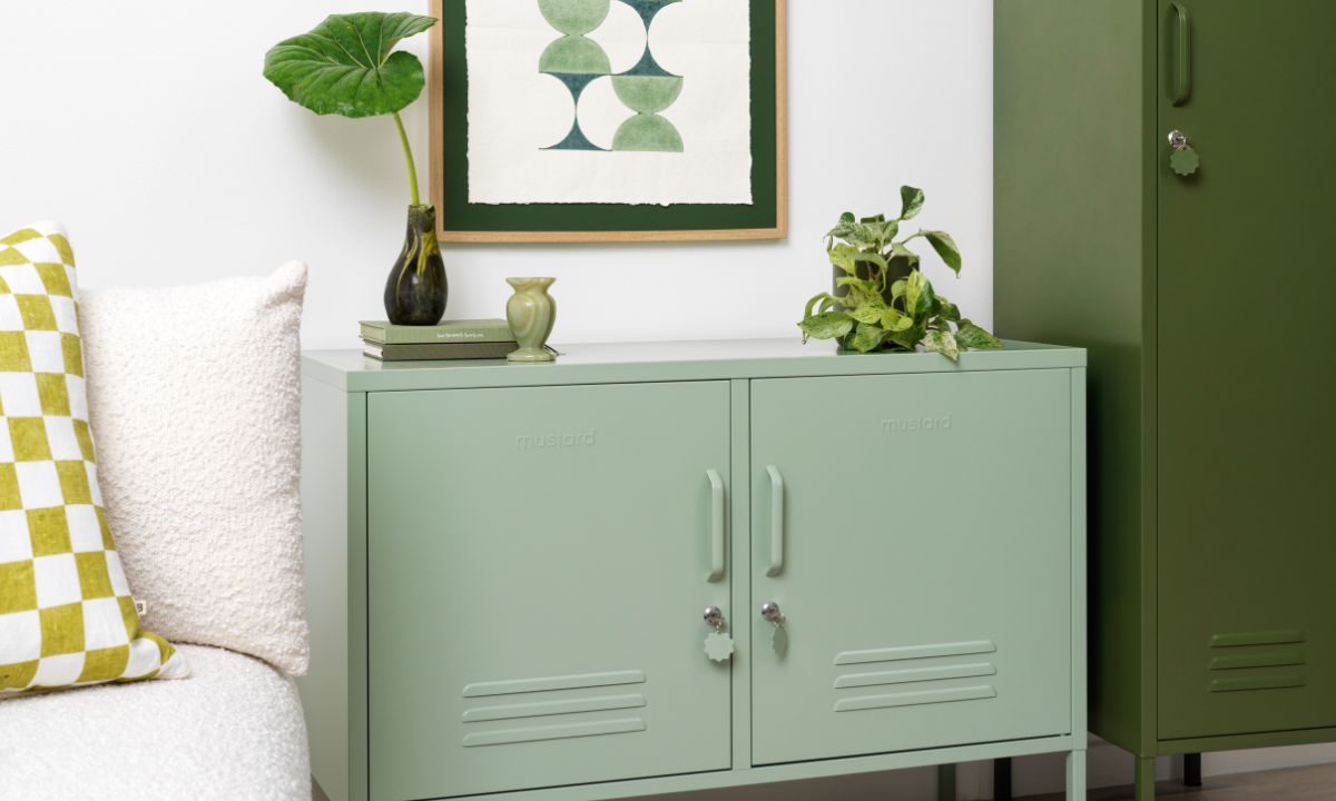 A Sage Lowdown sits next to an Olive Skinny locker. They are accessorised with leafy green plants, some green books and an artwork in shades of green.