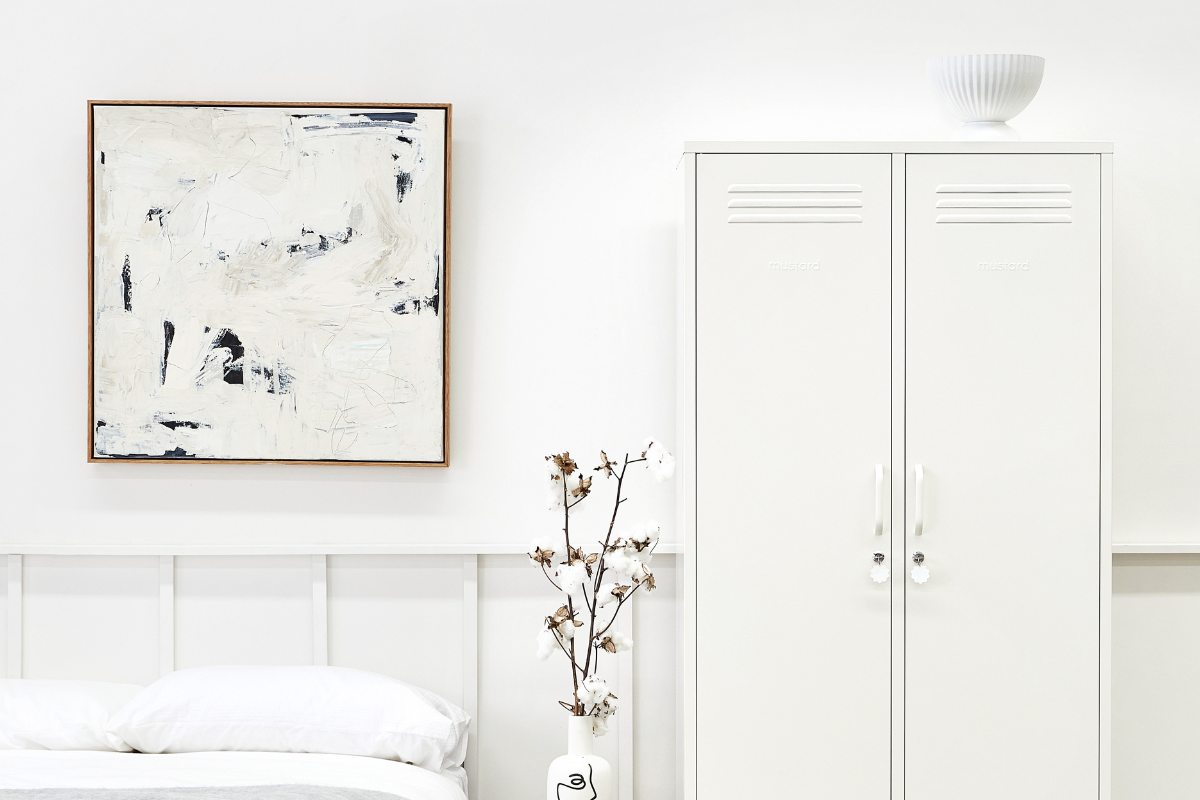 A White Twinny Locker stands next to a bed with white bed sheets.