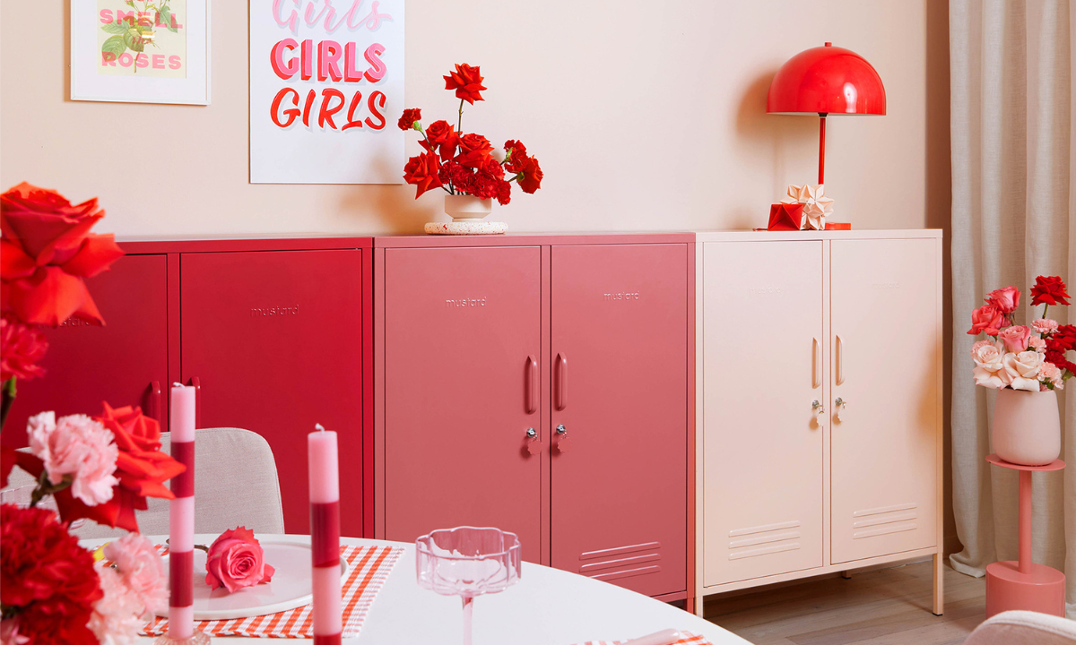A trio of Mustard Made Midi lockers in an ombre pattern ranging from red to blush pink. The space is filled with red and pink accessories and artworks.