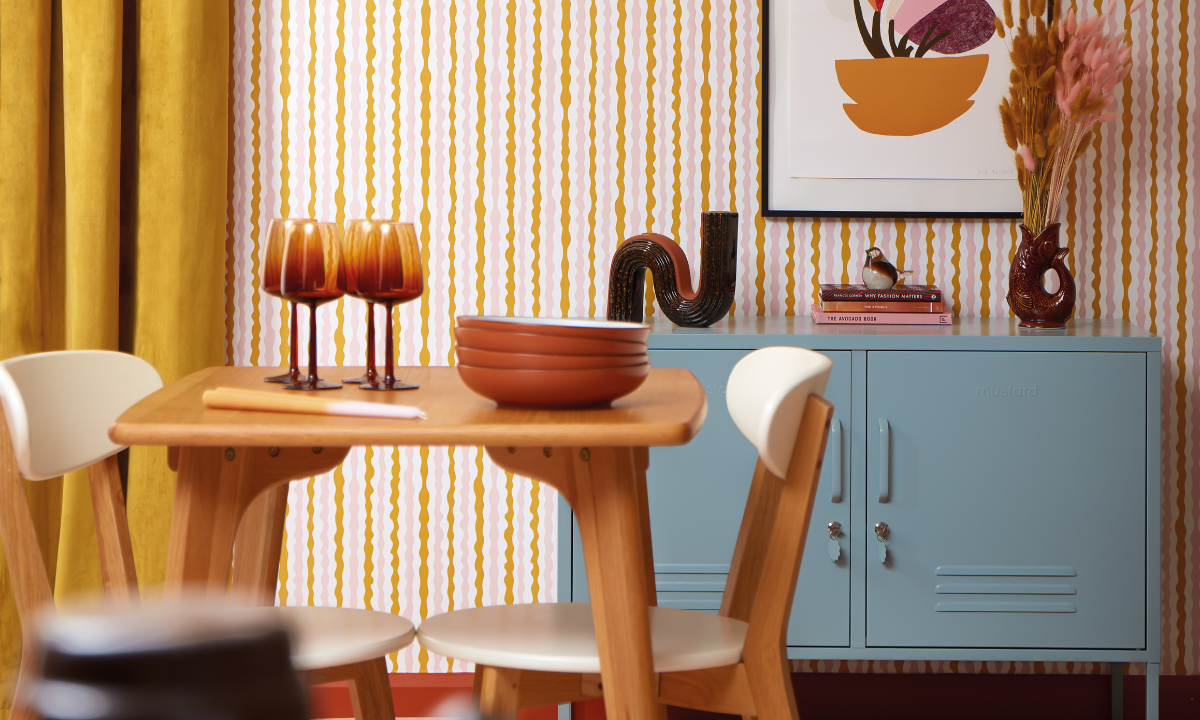 An Ocean Lowdown sits in a retro styled room against wallpaper with colourful, squiggly stripes.