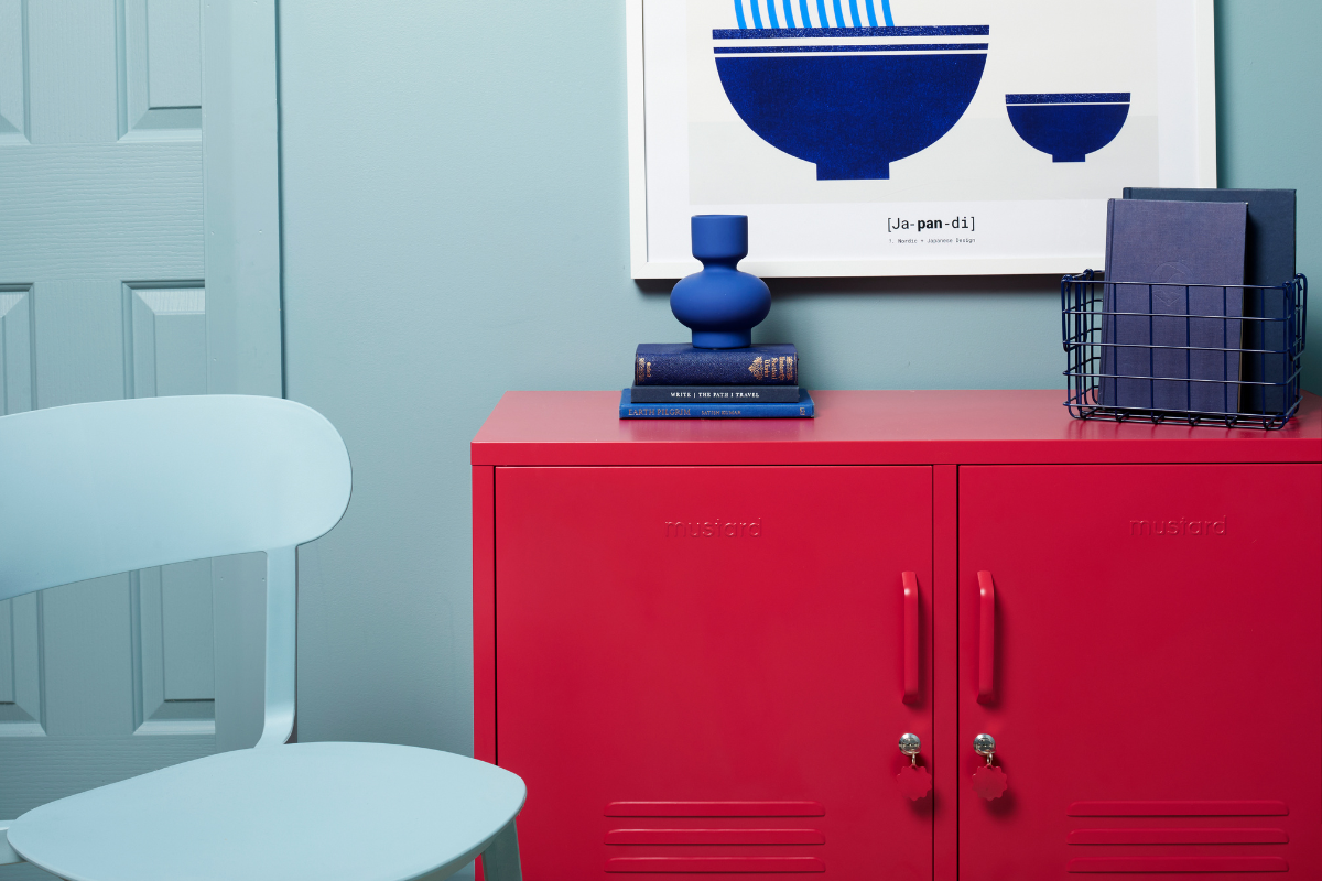 The Lowdown in Poppy against an Ocean blue wall.